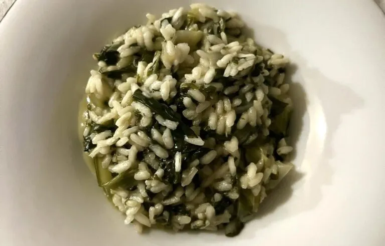 Chicchi's plain white risotto with swiss chard leaves mixed in, served in a white bowl.