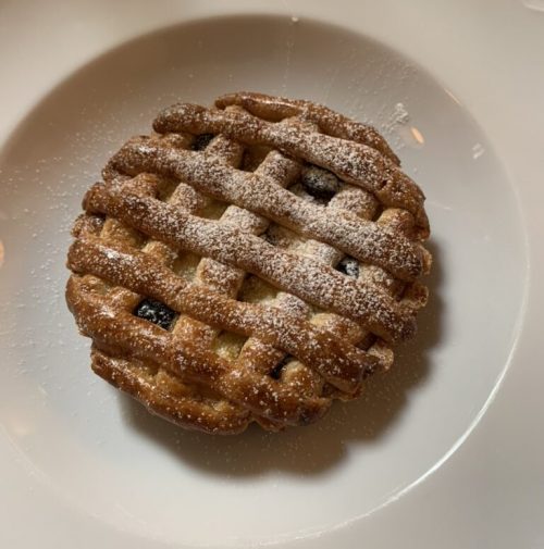 Ricotta and sour cherry tart, baked golden brown with lattice shortcrust top and dusted with icing sugar