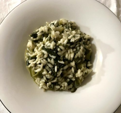 Chicchi's plain white risotto with swiss chard leaves mixed in, served in a white bowl.