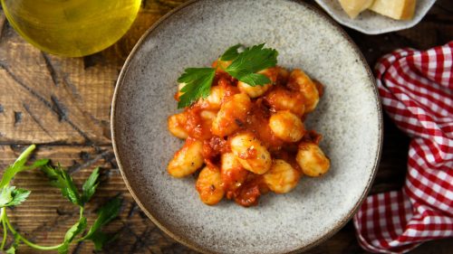 Gnocchi with tomato ad chicken sauce on a wood table with checked table cloth